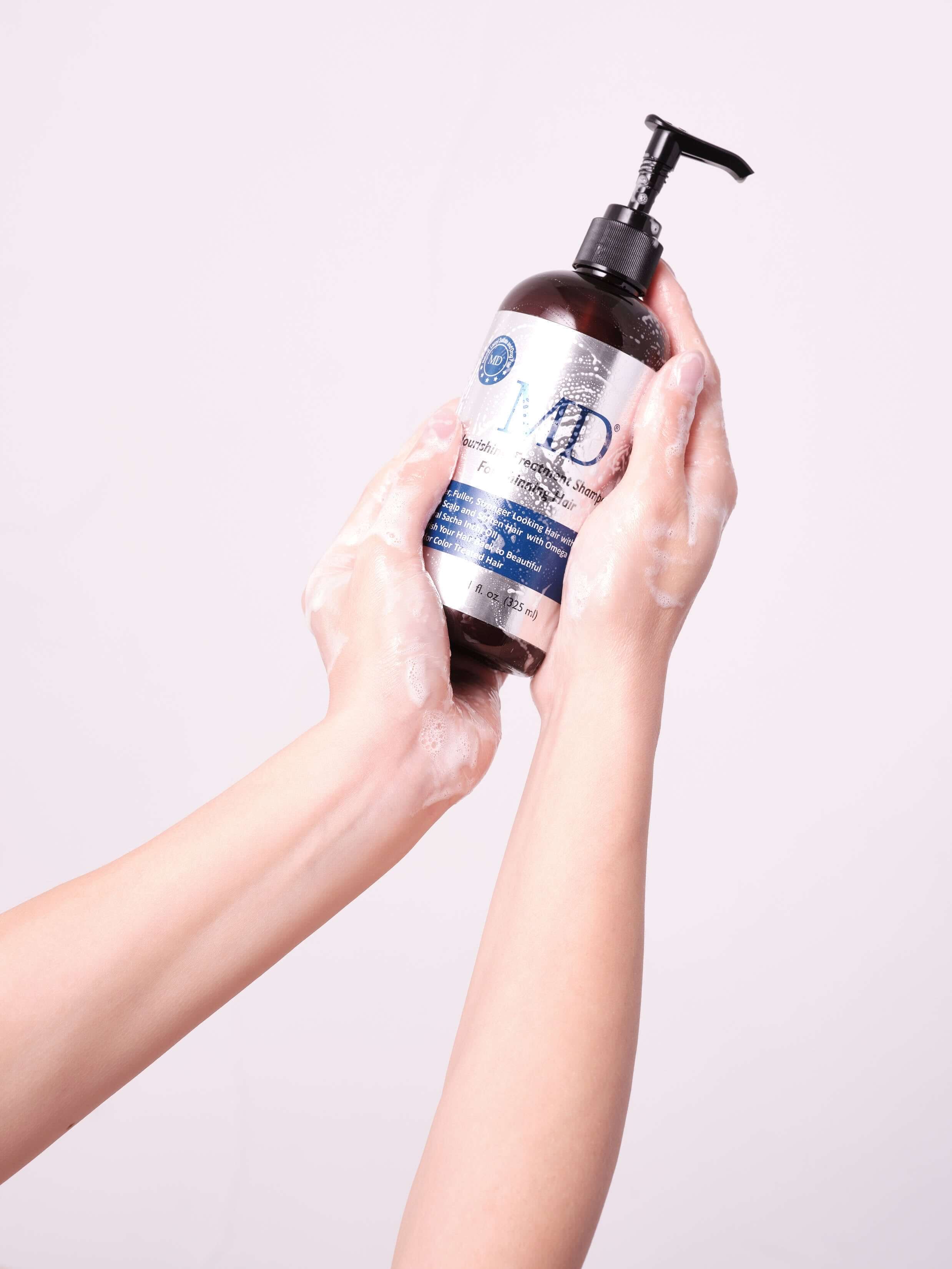 Both hands holding MD Nourishing Treatment Conditioner in shower, from MD Hair category for thinning hair and scalp hydration