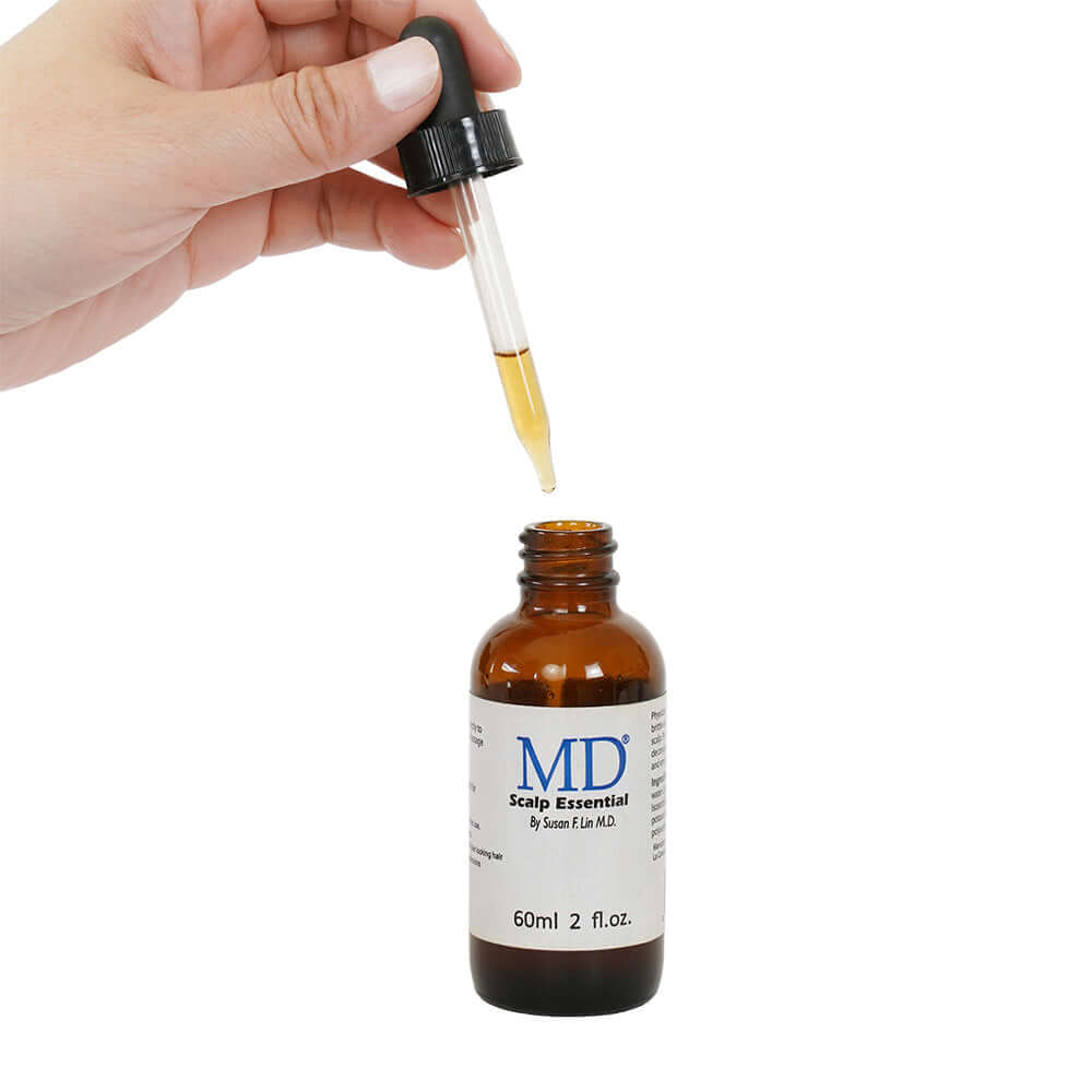 Hand taking dropper of MD Scalp Essentials – scalp treatment for oily, itchy scalp and thinning hair support