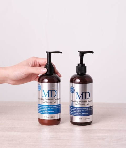 Hand holding MD Nourishing Treatment Shampoo and Conditioner from MD Hair, for thinning hair and scalp health