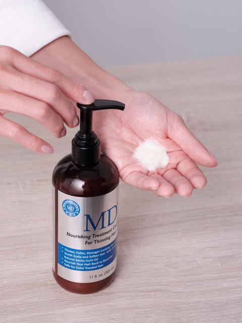 Hand pumping out MD  Nourishing Treatment Conditioner from MD Hair to show smooth, lightweight texture for thinning hair