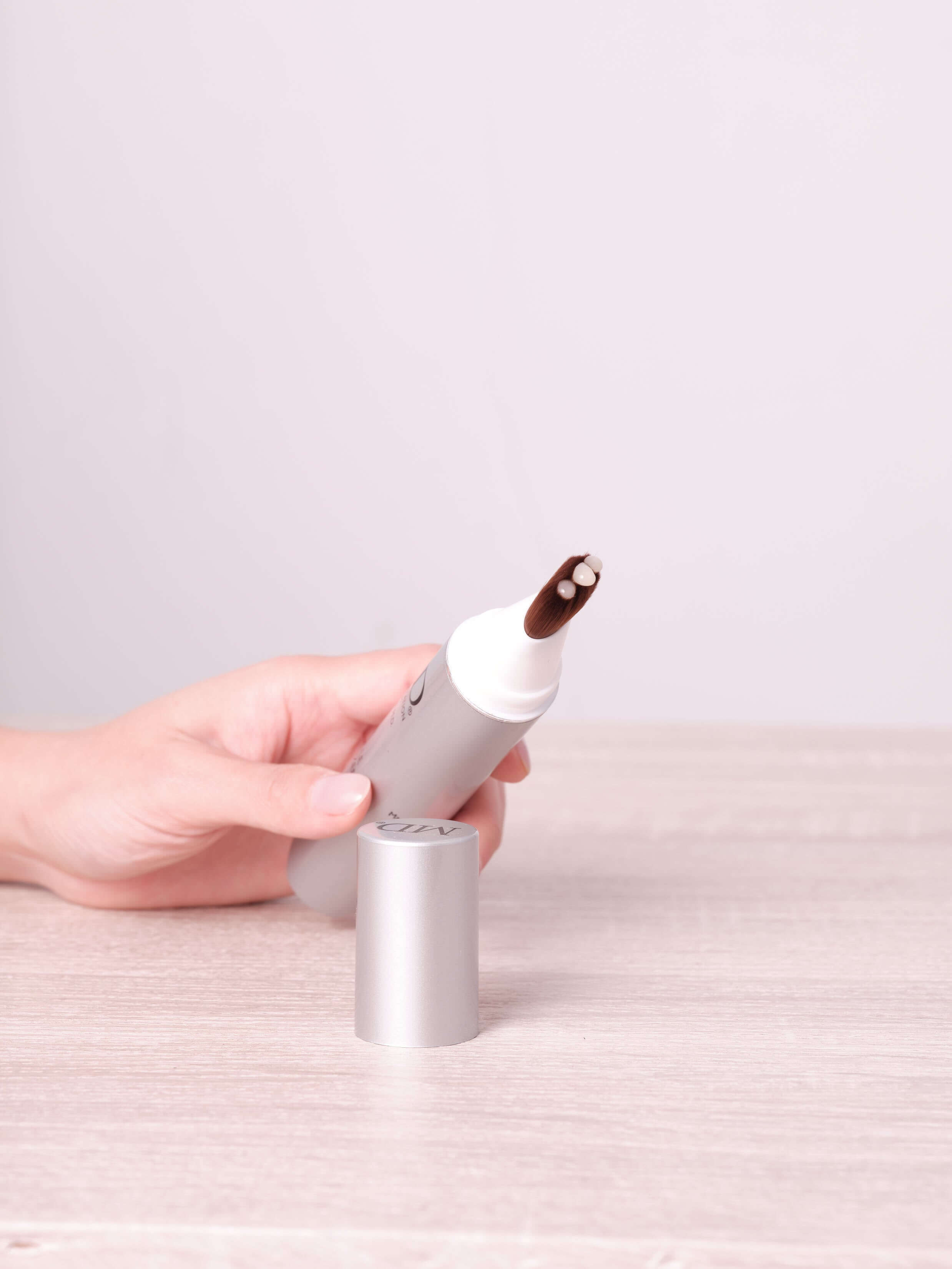 Hand holding MD® Follicle Energizer from MD Hair with visible brush tip and clear serum – targeted hair serum for thinning hair and scalp revitalization