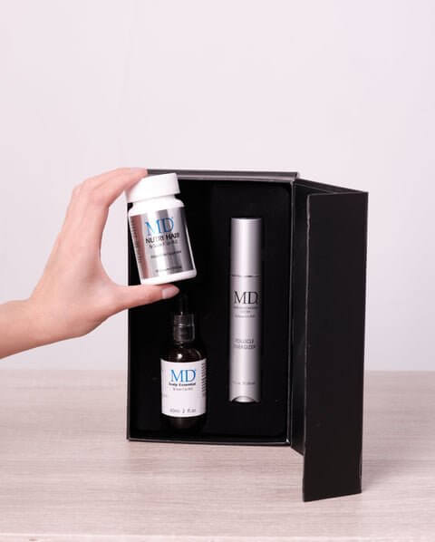 Hand reaching into MD Hair Restoration Kit to remove MD Nutri Hair supplement for thinning hair and hair loss support